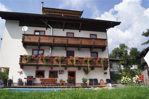 Ein charmantes Haus mit mehreren Balkonen, die mit Blumen geschmückt sind. Der Garten ist grün und einladend, ideal für entspannte Stunden.