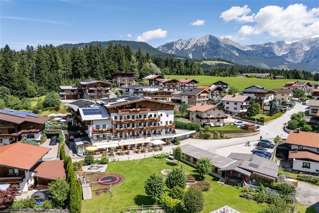Exterior view of the Hotel Alpenpanorama in Söll with garden, terrace, and view of the Tyrolean mountains.