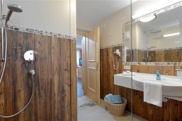 Helles Badezimmer im Hotel Alpenpanorama in der Ferienregion Wilder Kaiser mit Dusche, Waschbecken und hochwertigen Details.
