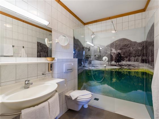 Modernes Badezimmer im Hotel Alpenpanorama in der Ferienregion Wilder Kaiser mit Dusche, großem Spiegel und alpinem Wa