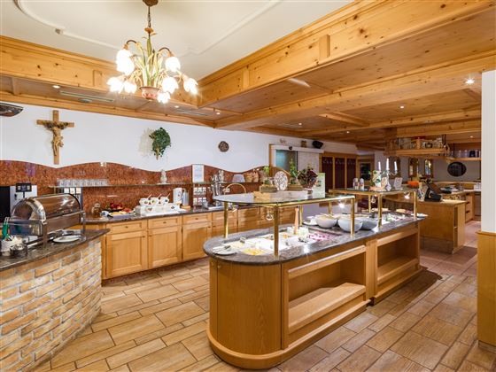 Heller Restaurantbereich im Hotel Alpenpanorama mit Buffetstation, Holzdecke und Tiroler Einrichtung.