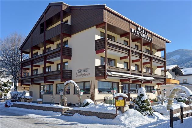 Ein attraktives Hotel mit Restaurant in einer schneebedeckten Umgebung. Die Fassade ist modern und einladend, umgeben von winterlicher Landschaft.