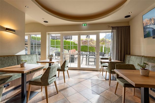 Ein einladendes Restaurant mit großen Fenstern und modernen Möbeln. Der Raum ist hell und freundlich, ideal für gesellige Treffen.