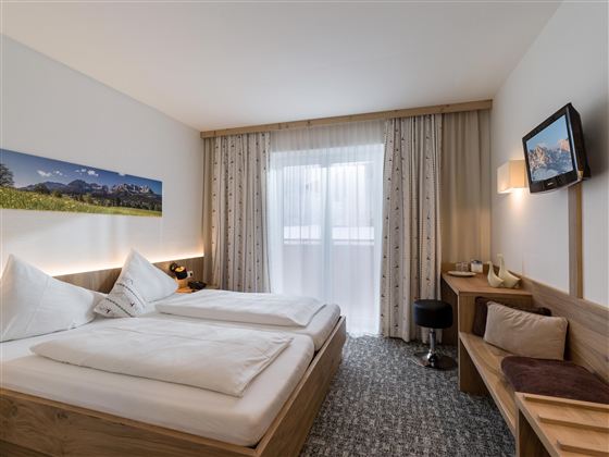 Ein gemütliches Hotelzimmer mit zwei Betten und modernem Design. Es verfügt über einen Schreibtisch und große Fenster, die für viel Tageslicht sorgen.