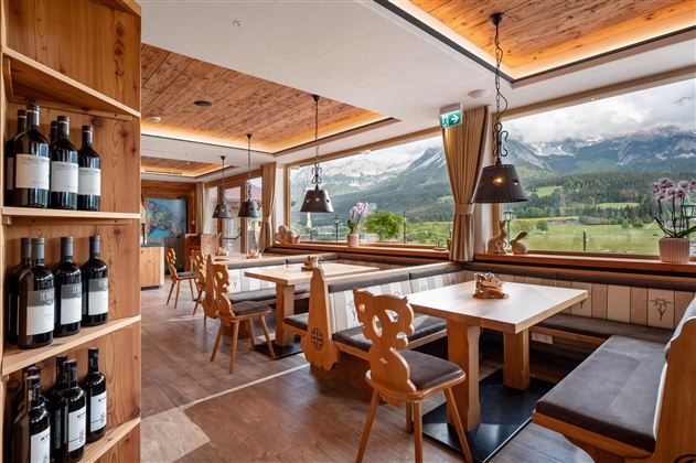 Een gezellig restaurant met houten interieur en grote ramen. Het uitzicht op de bergen en de wijnrekken zorgt voor een uitnodigende sfeer.