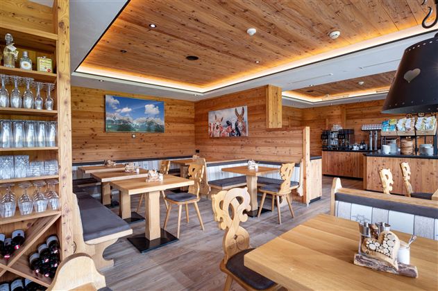 Een gezellig restaurant met houten wanden en moderne meubels. Tafels zijn netjes gedekt en een bar is op de achtergrond zichtbaar.