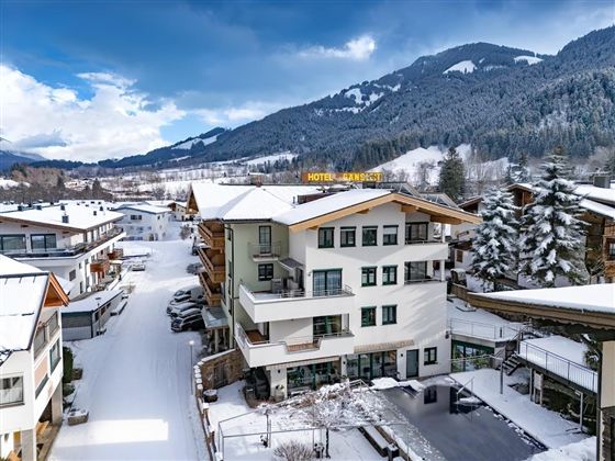 Ein Winterblick auf das Hotel mit schneebedeckten Dächern und umliegenden Bergen. Die Landschaft ist friedlich und einladend.