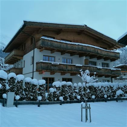A cozy chalet in winter with fresh snow. The balconies are made of wood and the surroundings are picturesque.