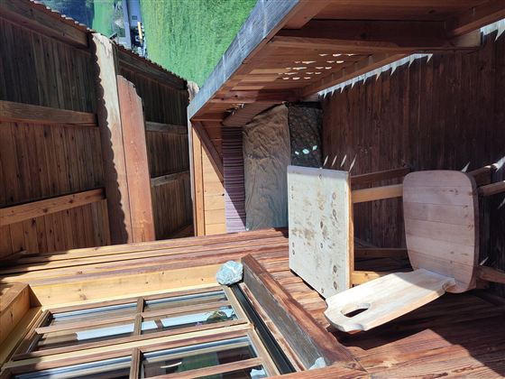 Een gezellige houten terras met een tafel en een stoel. Op de achtergrond zijn groene weiden en een prachtig uitzicht te zien.