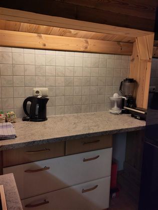 Een moderne keukeneenheid met een houten plank. Op het werkblad staan een waterkoker en een blender.