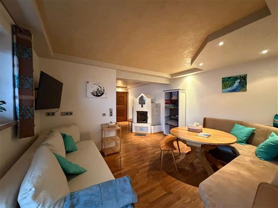 Een gezellige woon- en eetkamer met lichte muren en moderne meubels. De inrichting omvat een bank, een tafel en een open haard, omringd door een warme houten vloeren.