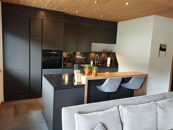 Modern, elegant kitchen with dark furniture and a central wood island. The rooms are designed to be bright and inviting.
