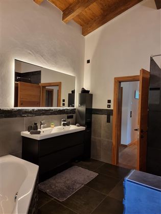 A modern bathroom with a wooden ceiling and elegant furnishings. There is a large sink, a bathtub, and a shower.