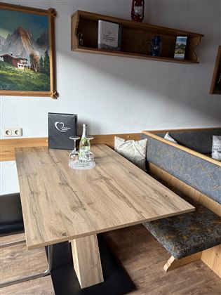 A cozy wooden table in a restaurant. In the background, there is a bench and some decorative items visible.