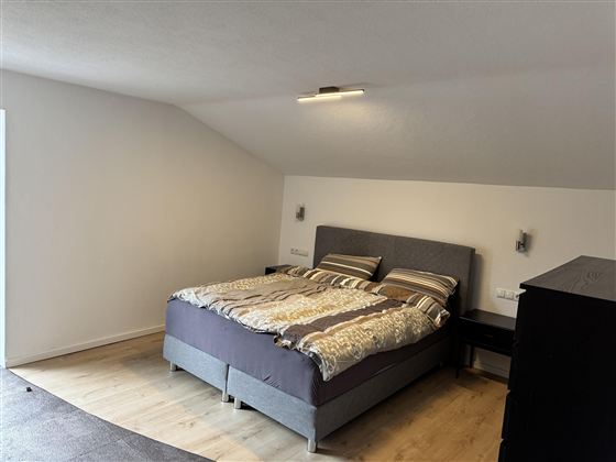 Ein gemütliches Schlafzimmer mit einem großen Doppelbett und modernen Möbeln. Der Raum hat eine helle Atmosphäre und einen Holzfußboden.