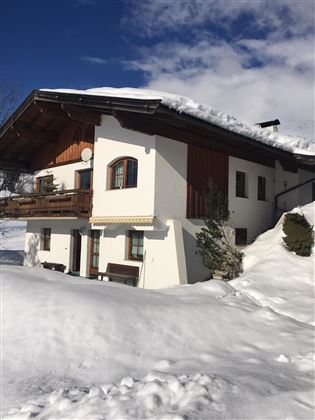 A charming house in the snow with a snow-covered roof. The surroundings are wintry and idyllic.