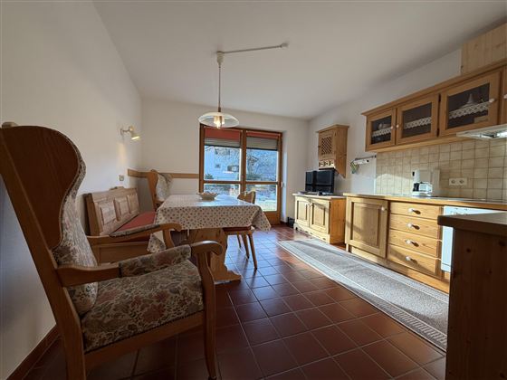 Eine gemütliche Ferienwohnung mit Holzdetails und viel natürlichem Licht. Der Wohnbereich umfasst einen Essplatz und eine kleine Küche.