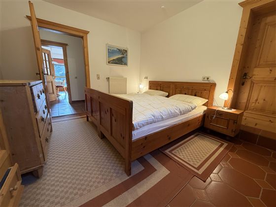 Ein gemütliches Schlafzimmer mit einem Holzbett und Nachttischen. Der Raum hat einen warmen, einladenden Eindruck und ist gut beleuchtet.