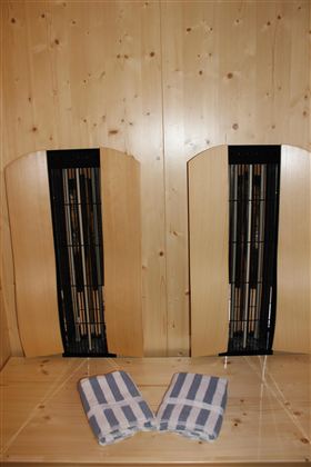 Twee houten bankjes staan tegen een muur, met twee handdoeken in het midden. De kamer heeft een warme, uitnodigende sfeer.