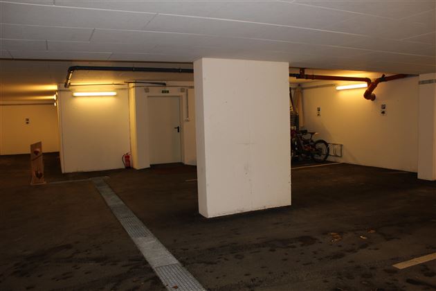 Ein leerer Parkplatz mit einem Säule in der Mitte. Die Wände sind hell und die Beleuchtung ist weich.