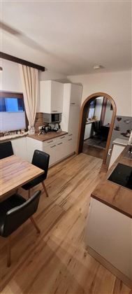 A modern kitchen with a wooden table and black chairs. The room has a warm and inviting look.