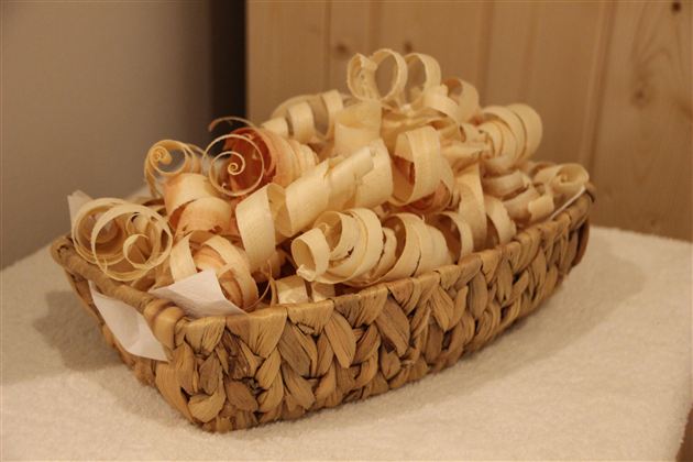 Ein geflochtener Korb voller Zirbenspäne. Die Späne sind in verschiedenen Formen und Farben und wirken dekorativ.