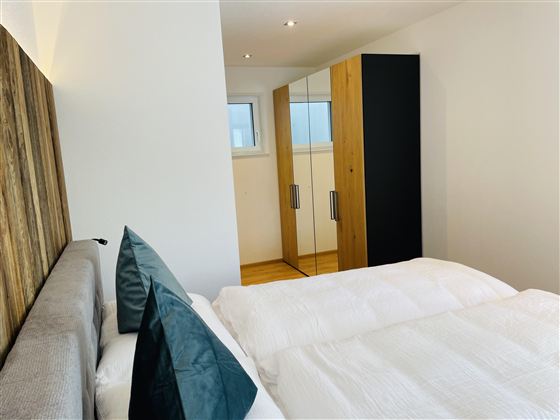 A modern bedroom with a large bed and an elegant wardrobe. The rooms are designed to be bright and friendly.