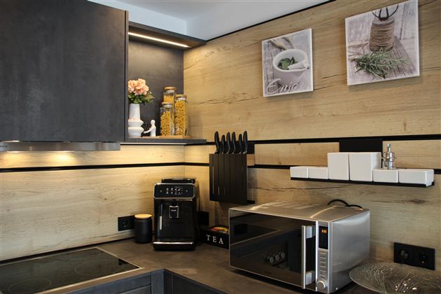 Auf der Arbeitsplatte steht ein Kaffeevollautomat, eine Mikrowelle und dekorative Elemente.