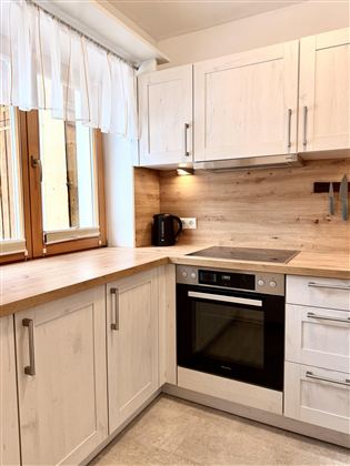 A modern kitchen with bright, wood-like furniture and integrated technology. The window provides natural light and an inviting atmosphere.