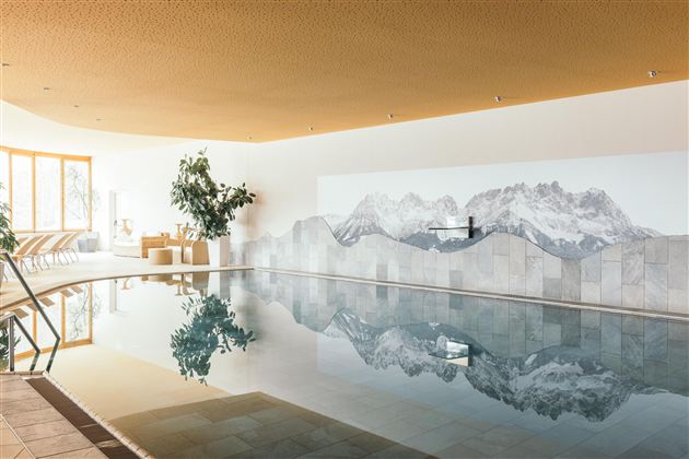 Een elegante binnenzwembad met een berglandschap op de achtergrond. De sfeer is rustig en ontspannend, ideaal om te ontspannen.