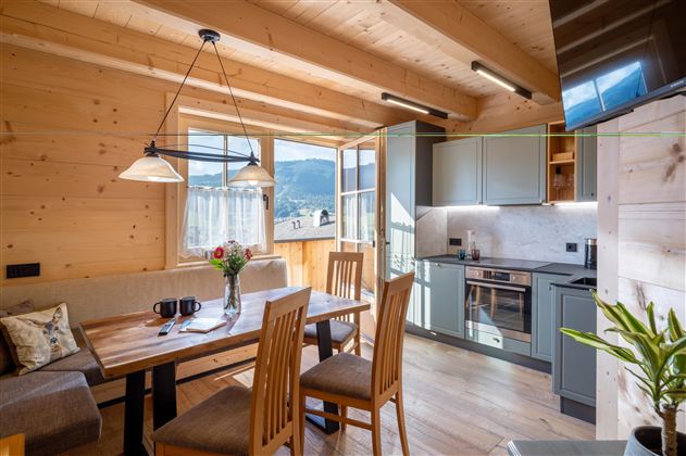 Een gezellige keuken met houten plafonds en een grote eettafel. De ramen bieden een prachtig uitzicht op het landschap.
