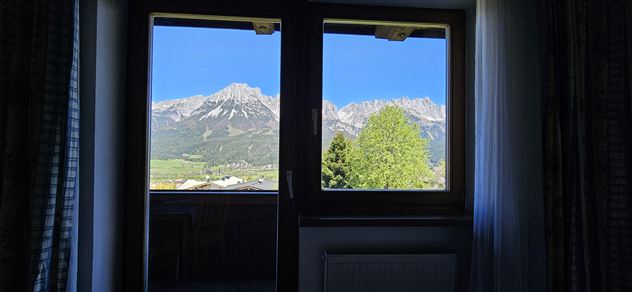 Een prachtig uitzicht op de bergen door een raam. De heldere blauwe lucht aanvult het schilderachtige landschap.