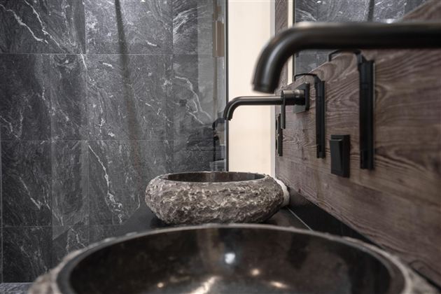 Een moderne badkamer met elegante zwarte wastafels en stijlvolle kranen. De wanden zijn in een eenvoudige grijze design gehouden.