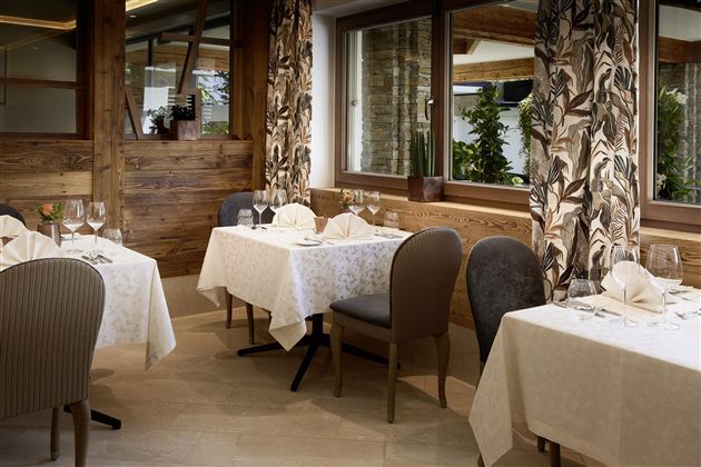 An elegant restaurant with decorated tables and stylish chairs. Large windows provide plenty of daylight and a cozy atmosphere.