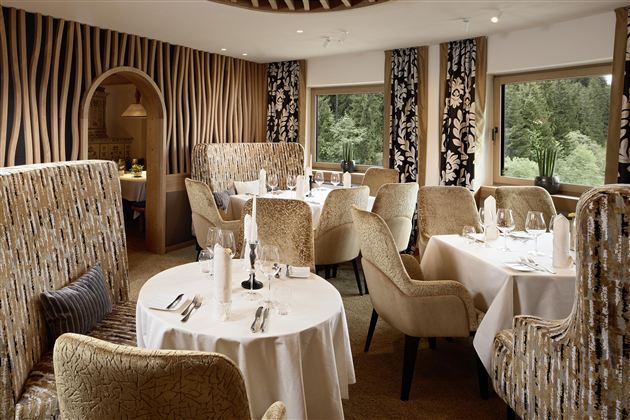 An elegant restaurant with stylish seating and tasteful decoration. Large windows provide a view of the greenery.