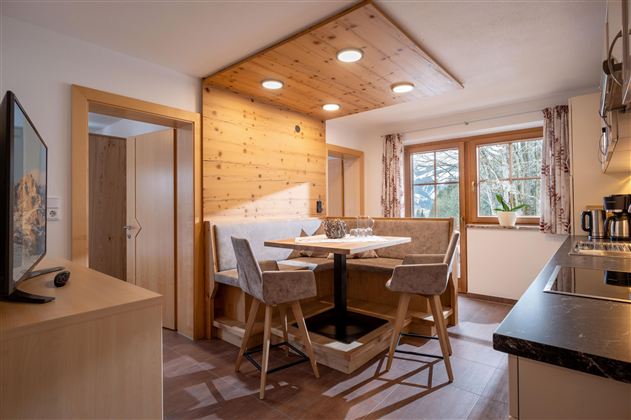 Een gezellige keuken met een eetgedeelte en moderne meubels. Veel daglicht stroomt door de ramen en creëert een uitnodigende sfeer.