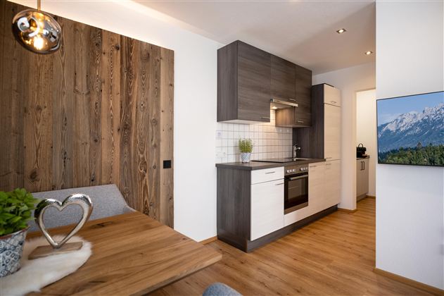 Eine moderne Küche mit Holzdetails und einem hellen Raum. Der Esstisch hat eine gemütliche Atmosphäre und die Wände sind hell gestaltet.