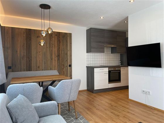 Eine moderne Wohnküche mit Holzdetails. Der Raum ist hell und einladend, mit einer gemütlichen Sitzecke.