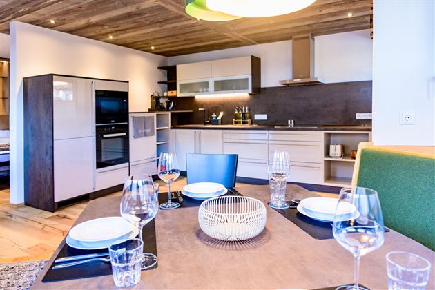 A modern kitchen with elegant furniture and high-quality appliances. The dining table is beautifully set and invites you to eat.