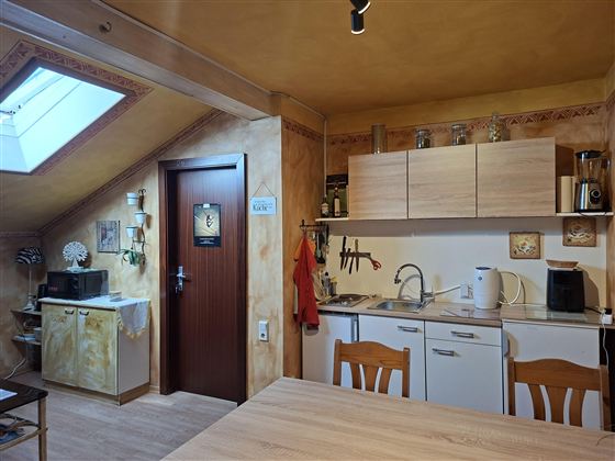 A cozy kitchen with wooden cabinets and a large table. A skylight provides plenty of daylight.
