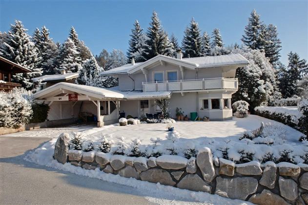 Our house in the snow, surrounded by snow-covered trees.
