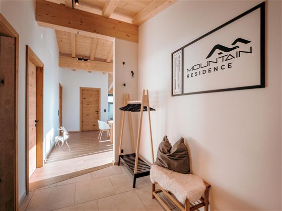 Ein heller Flur mit Holzdetails und einem modernen Design. An der Wand hängt ein Schild mit der Aufschrift "Mountain Residence".
