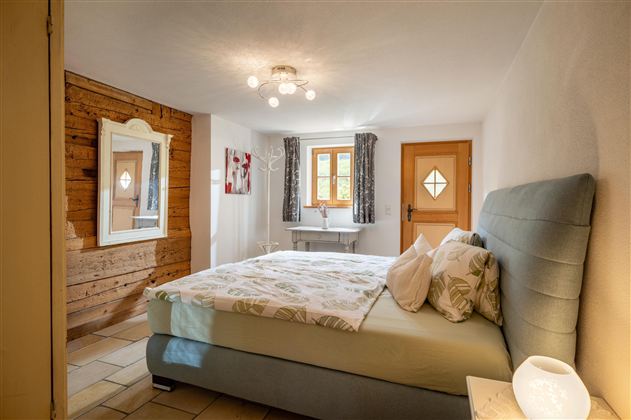 Ein gemütliches Schlafzimmer mit einem großen Bett und hellem Holzdekor. Das Zimmer ist gut beleuchtet und lädt zum Entspannen ein.