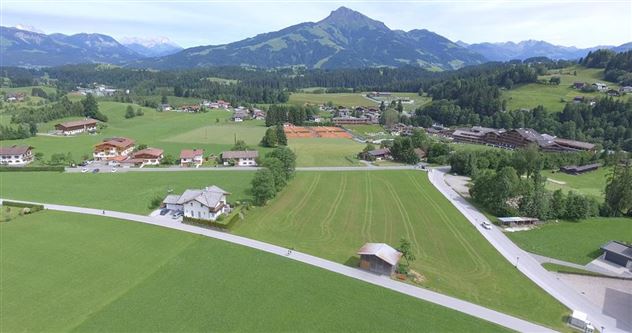 A picturesque landscape with several houses and lush green meadows. The surroundings feel calm and rural.