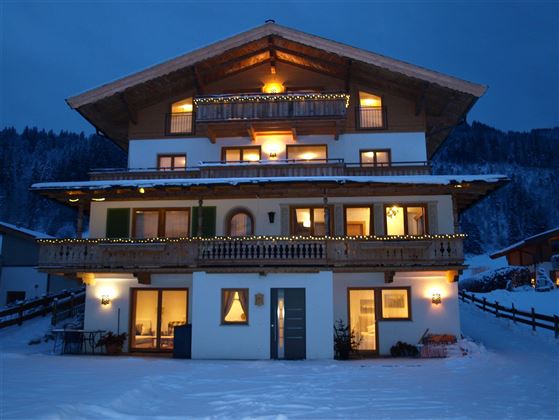 A cozy chalet in the snow with glowing windows. The surroundings are calm and wintry, ideal for a relaxing retreat.