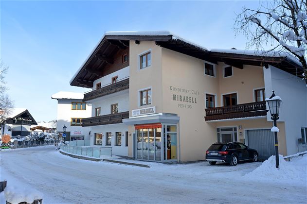 A cozy building in the snow that serves as a guesthouse. The surroundings are wintry with snow-covered streets and trees.