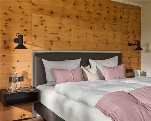 Zimmer mit Leinenbettwäsche und Zirbentäfelung.