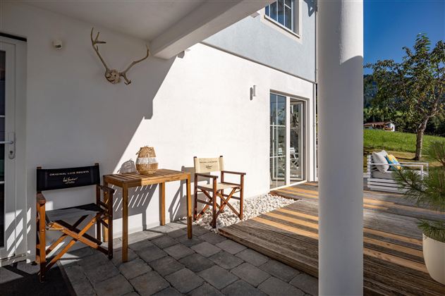Eingangsbereich und Zugang zur großzügigen Holzterrasse, die zum Verweilen einlädt. Modernes Terrassenmöbel für gemütlichen Kaffeegenuss oder längerfristiges Verweilen auf einer fein gepolsterten Terrassenlounge für unvergessliche Urlaubsmomente.
Der Zutritt zum Appartement erfolgt unkompliziert, einfach und selbständig über ein Zahlenschloss zur Schlüsselentnahme im Eingangsbereich.