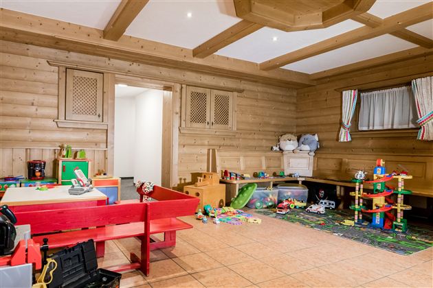 An inviting playroom with wooden paneling. There are toys and furniture in bright colors for children.