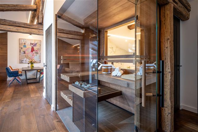 A modern sauna area with glass walls and wooden details. The room radiates a relaxing atmosphere.